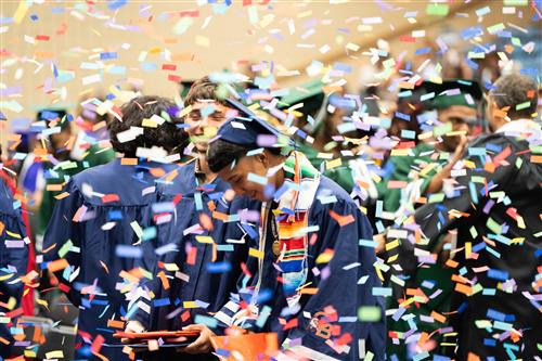 Graduates celebrating behind colorful confetti!